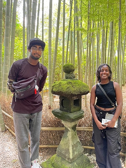 Two students pose for photo with lantern in Japanese bamboo forest