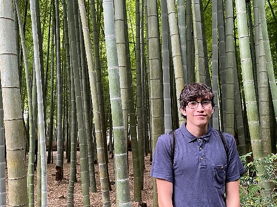 Student with glasses posing for photo in bamboo forest