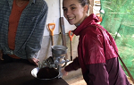 Student smiling while grinding coffee at plantation in Costa Rica. 