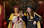 2 Students wearing medieval clothes sitting on throne and clinking chalices