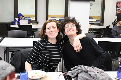 A female student and a male student smile for the camera during a dinner for students who participate in Center for Diversity and Inclusion activities. The female student on the left has her arm around the male student. 