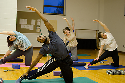 Landmark College students do a side stretch during a yoga class.