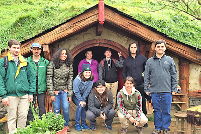 Students in front of the round door of a home on the Hobbiton movie set in New Zealand