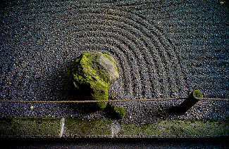Semicircular lines drawn in gravel around moss-covered stone