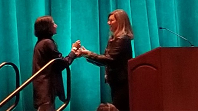 Dr. Manju Banerjee is greeted by Beth McGaw, outgoing President of LDA as she ascends the stage to accept her award at the LDA Annual Conference in Orlando, Florida.